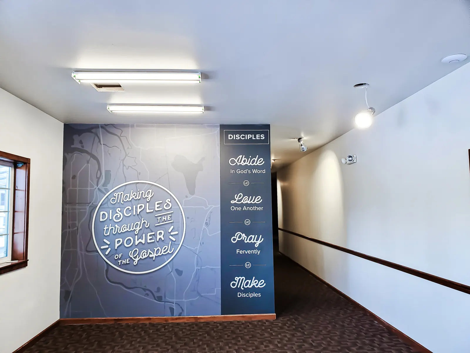 Church hallway wall wrap with a "Making disciples through the power of the Gospel" seal and four values: Abide, Love, Pray and Make Disciples