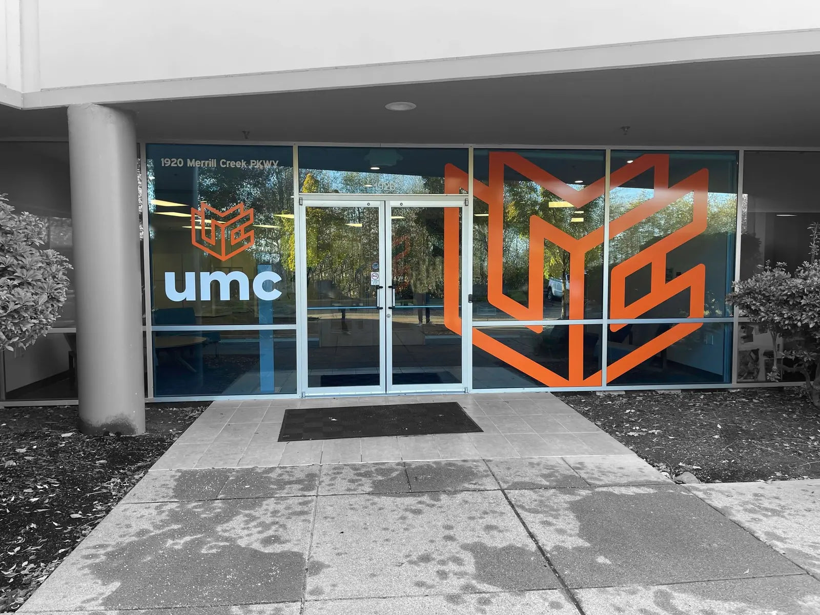 Commercial building entrance with a large orange UMC logo window graphic and white UMC lettering across the front glass