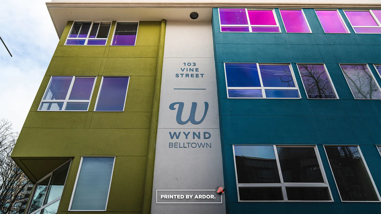 Upper-floor windows with pink and violet color window film on the WYND Belltown apartment building at 103 Vine Street
