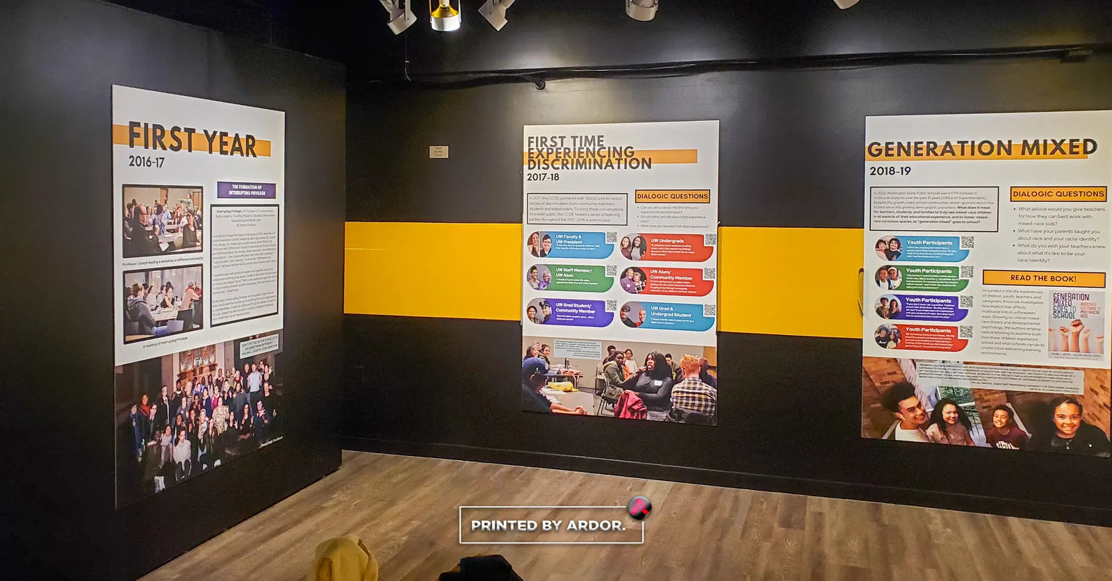 Museum exhibit wall with black and yellow wall wrap and large printed history panels titled First Year and Generation Mixed
