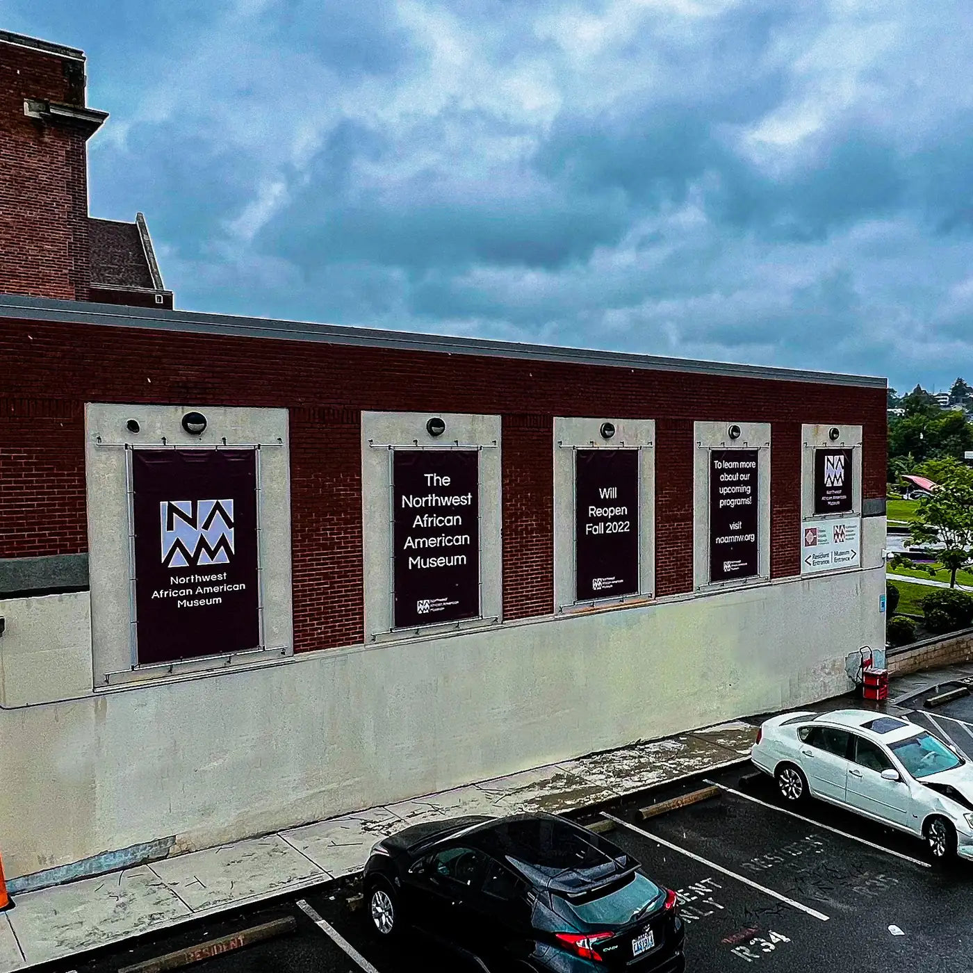 Vinyl banners in the windows of the Northwest African American Museum's brick building announcing a fall 2022 reopening